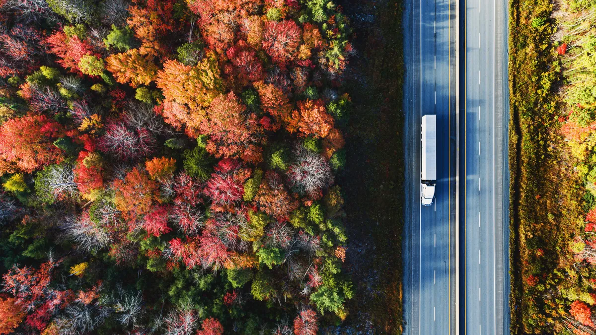 Aerial view of a semi truck driving on a highway on an October morning.