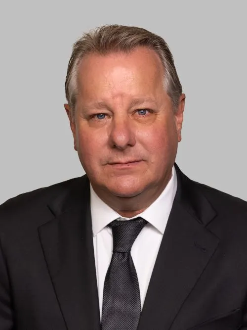Headshot of a white man in a suit and tie with graying hair