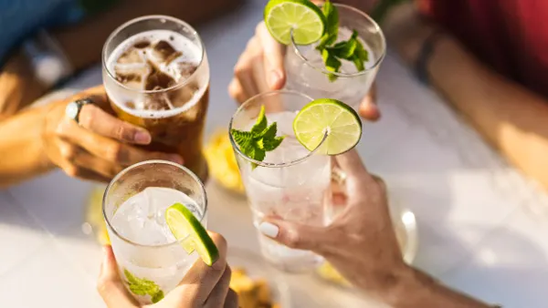 A closeup of four people's hands holding drinks in a toast.