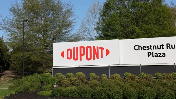 A red and white DuPont sign next to a black and white Chesnutt Run Plaza sign next to it.