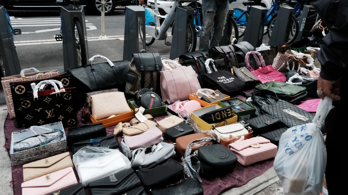On a sidewalk, multiple handbags are displayed with handles wrapped in paper.