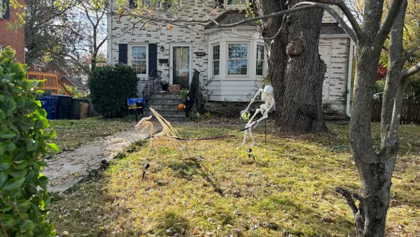 A skeleton walks a skeleton pet in a yard.
