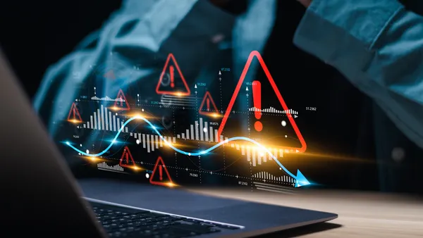 Businessman use laptop with virtual world economic growth chart with red warning sign