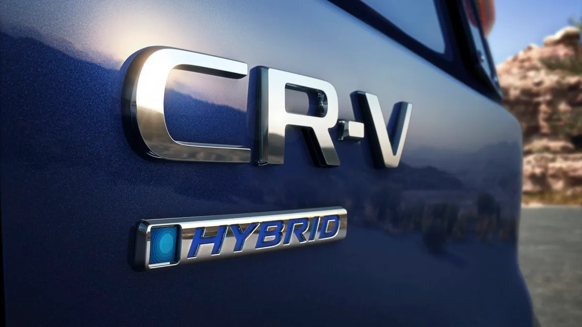 An emblems with the text CR-V and hybrid on the rear of a 2023 dark blue Honda CV-V crossover.