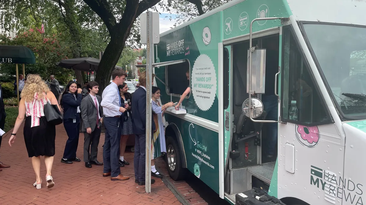 People walk around in front of a truck offering free donuts.