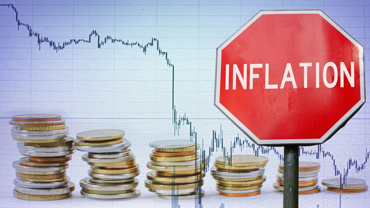 Warning sign with the word "inflation" appears against a background with stacks of coins.