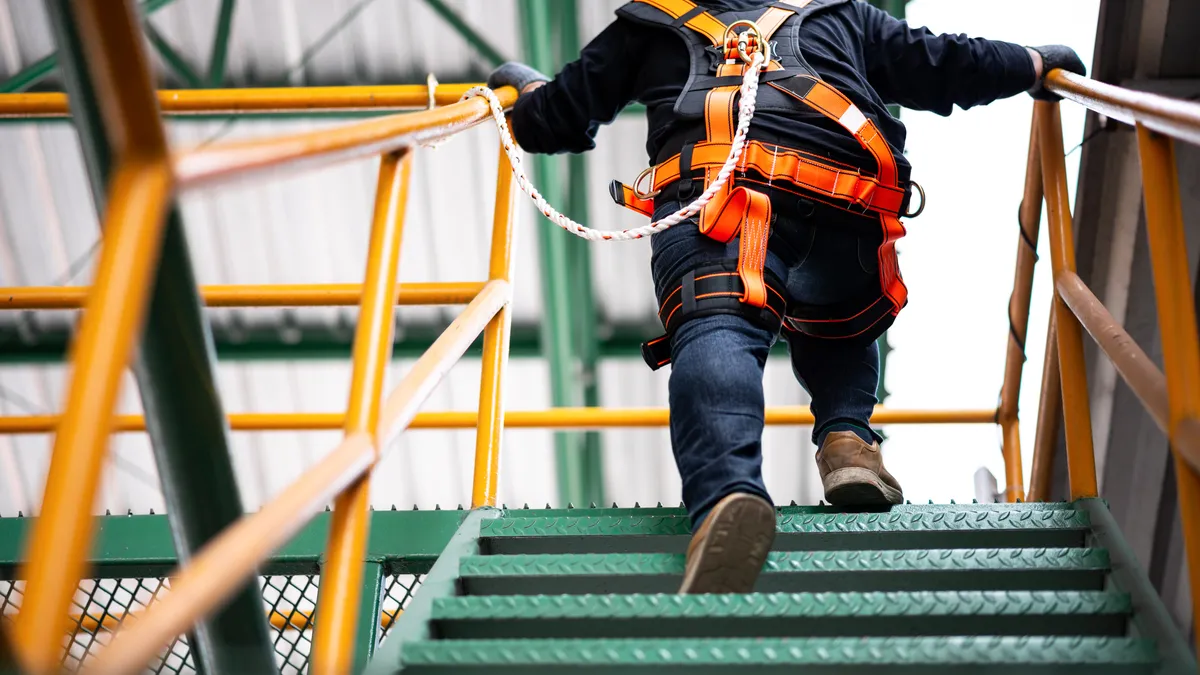 Construction worker wearing safety harness and safety line working at high place.