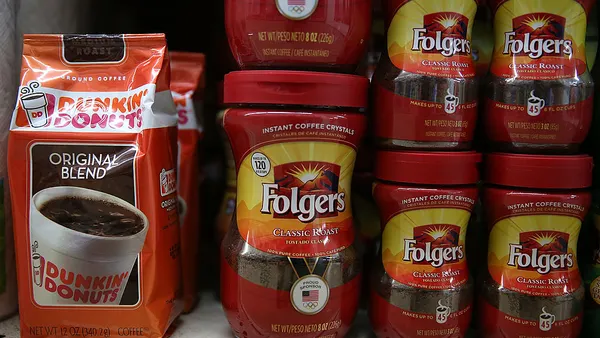 Packages of Dunkin' Donuts and Folgers coffee are displayed on a shelf at a grocery store.