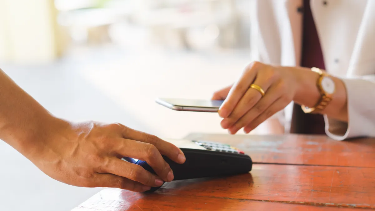 A consumer pays by tapping the phone to a point-of-sale device.