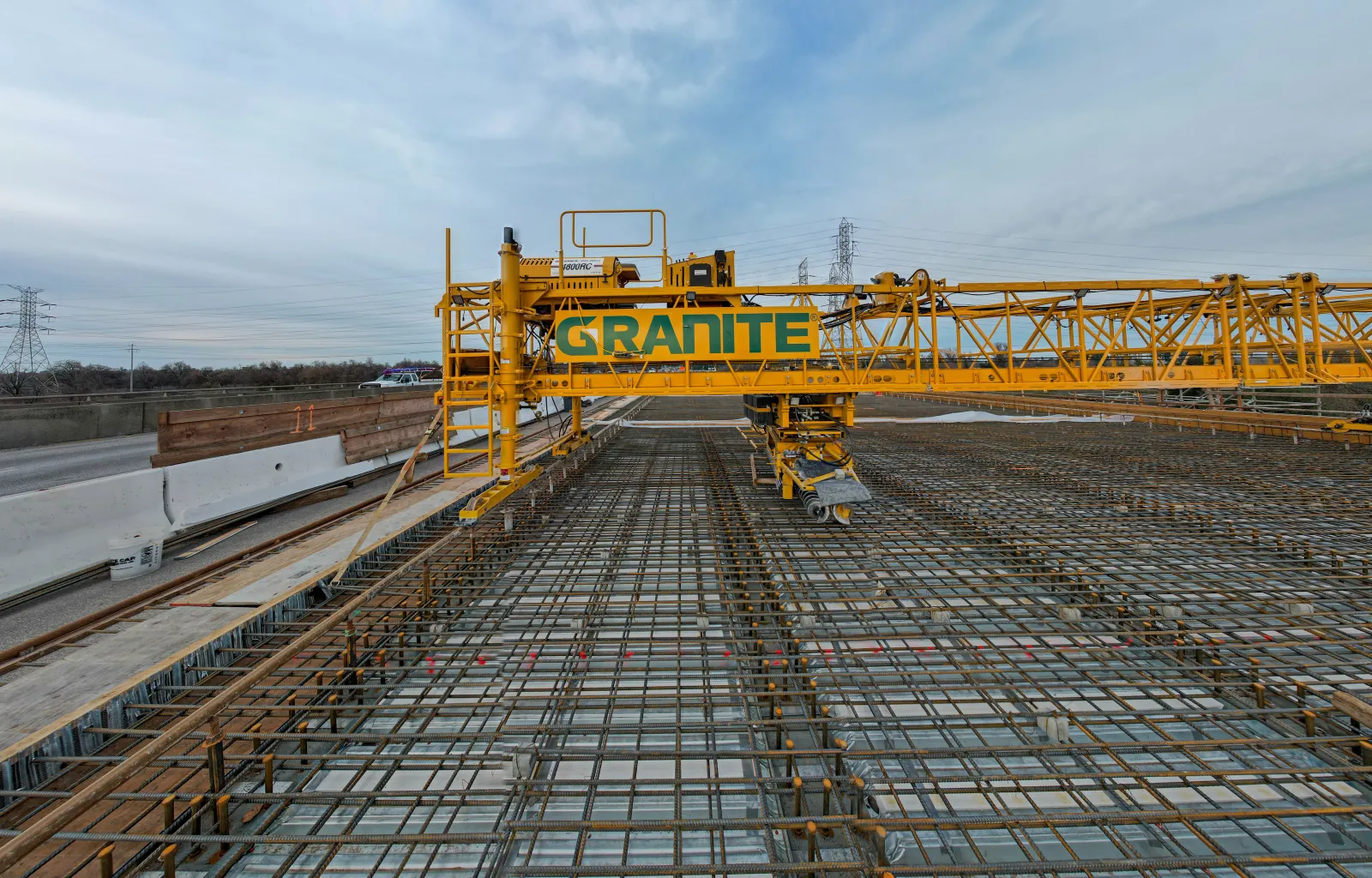 A large yellow bridge decking scaffolding machine prepares to pour concrete.