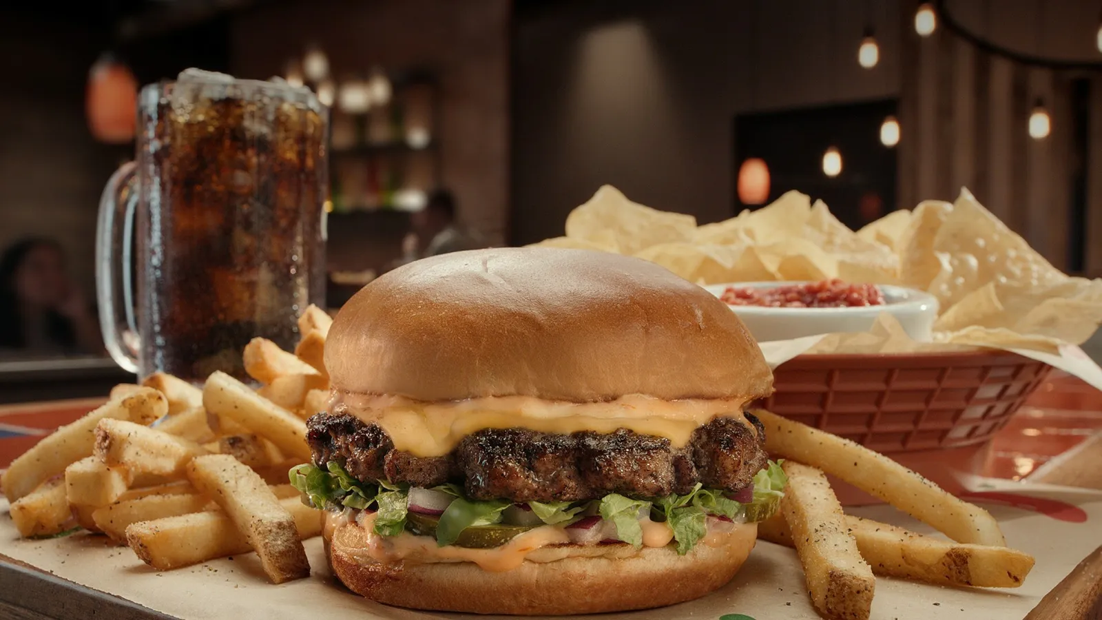 A Chili&#x27;s Burger framed by fries and a drink.