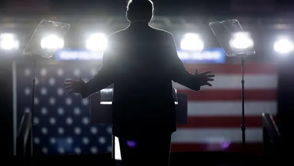 Donald Trump stands in front of bright lights