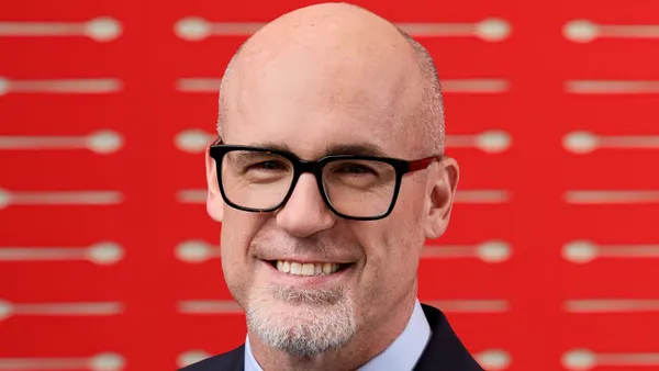 A photograph of a persn in front of a red background.