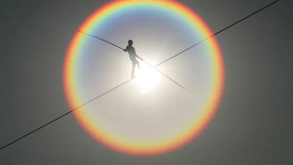 A tightrope walker advances in sunshine.