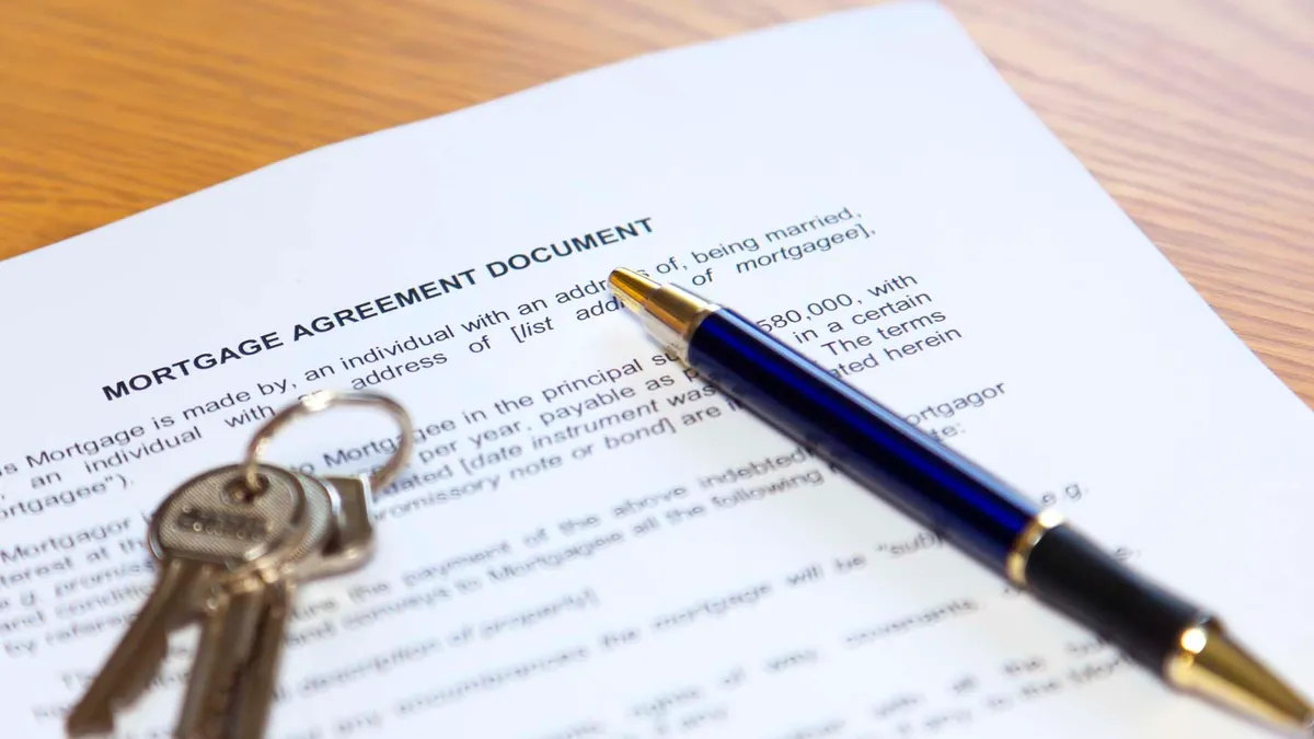 A set of keys and a pen sit on top of a mortgage application.