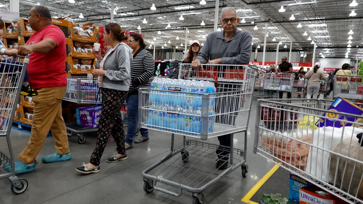 Customer with water in his cart is shown shopping inside a Costco store.