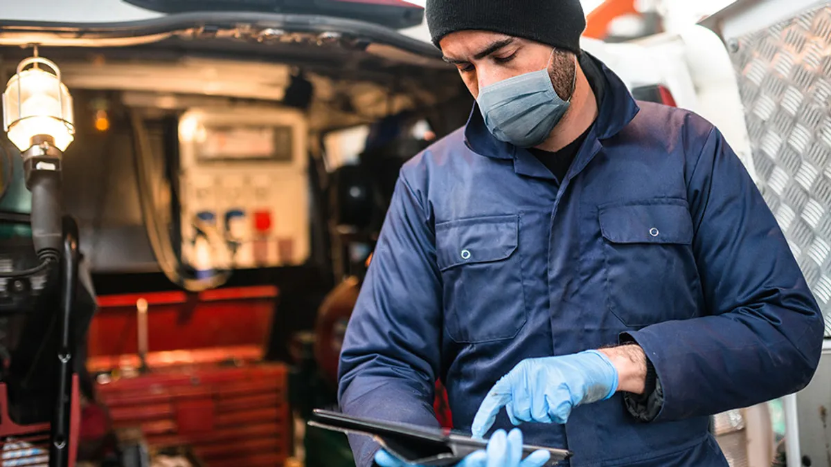 A man looking at a tablet by a truck.