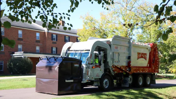 A trash truck picks up a dumpster