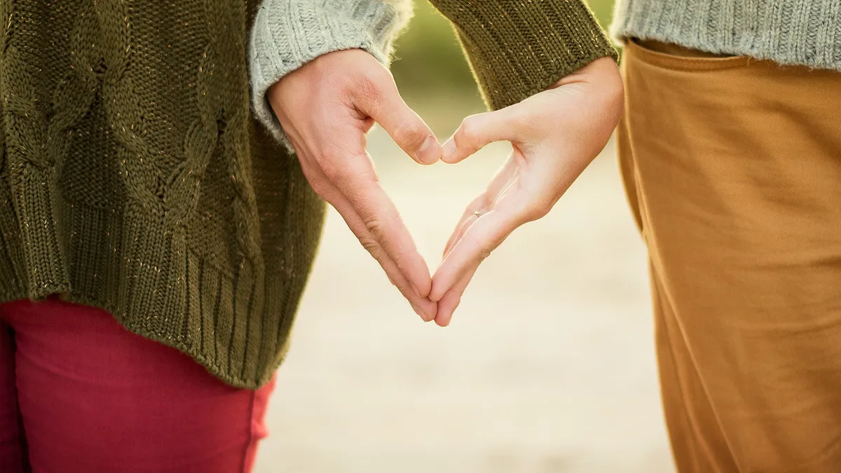 Two people forming a heart with their hands.