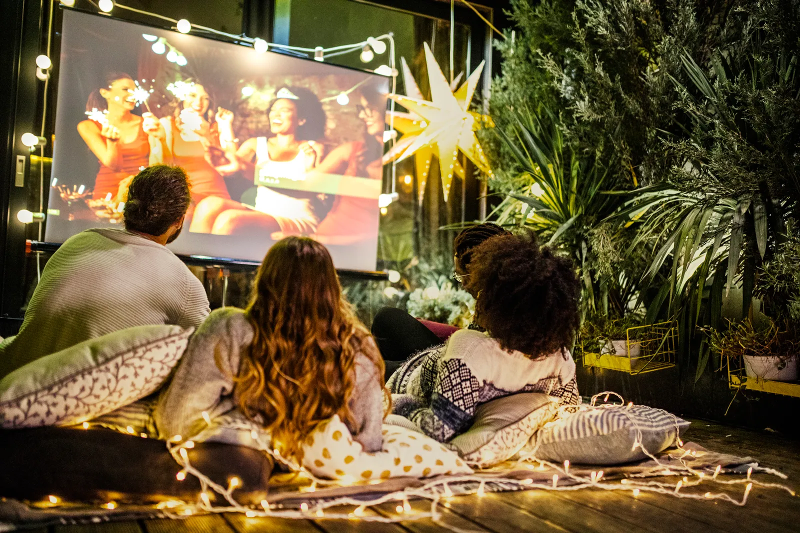 Friends watch a movie outside on a home projector