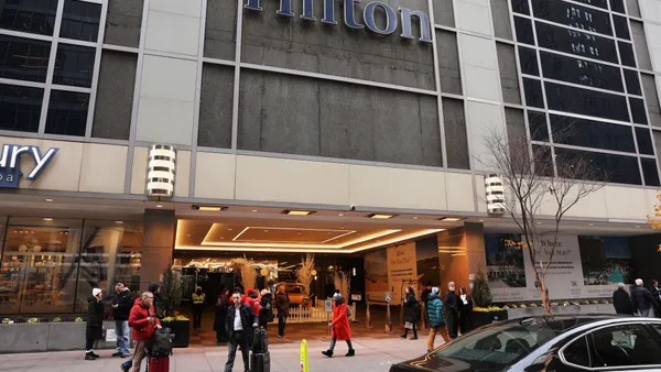 Pedestrians walk and stand on the sidewalk outside New York Hilton Midtown.