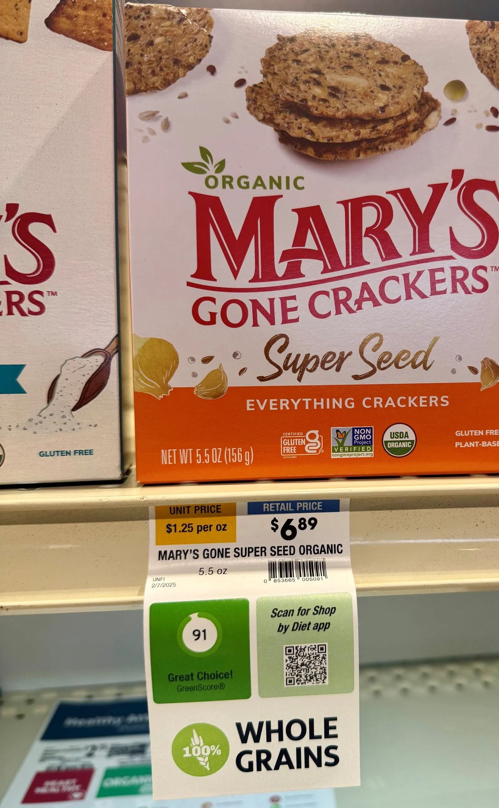 A box of crackers above a price tag on a grocery store shelf.
