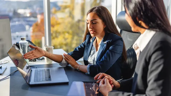 Two hispanic women executives discuss future plans and ideas at work in the office