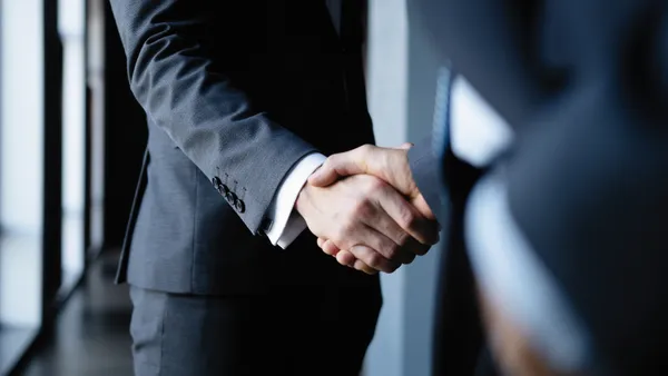 Two businesses executives shake hands in office