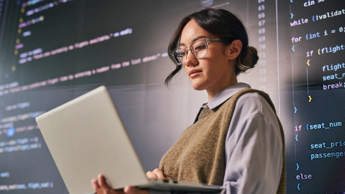 Young woman reviewing code on a laptop