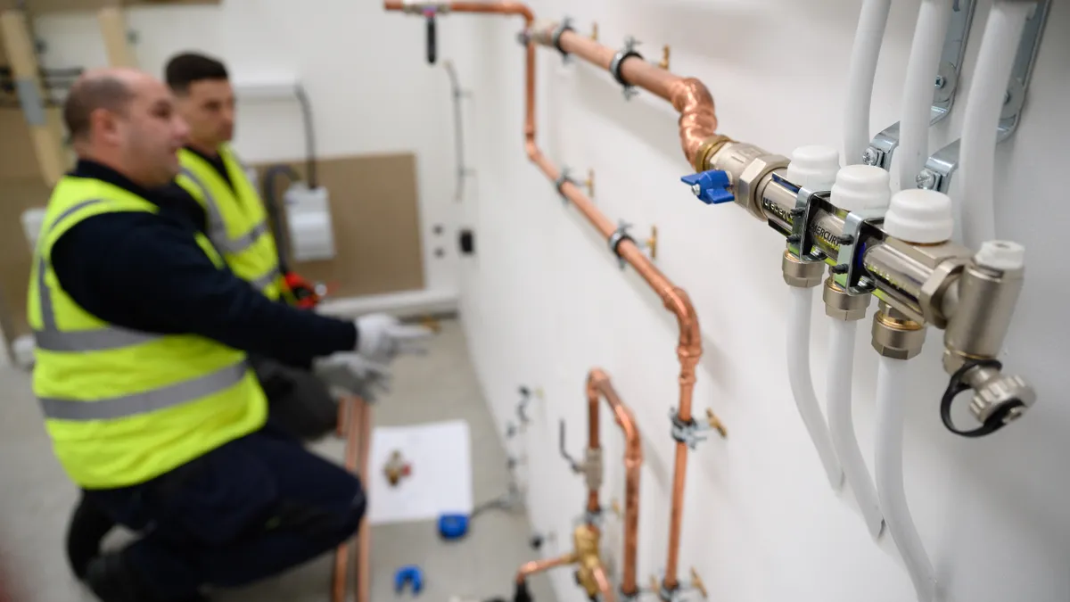 Technicians install heat pump systems at a training facility.