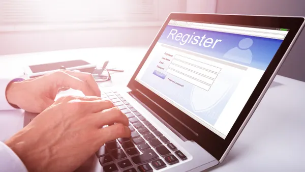 A person fills out an online registration form using a laptop computer.