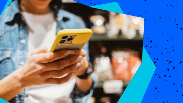 A person in a denim shirt uses a yellow smartphone, with blurred store shelves in the background. The image has a blue, speckled border.