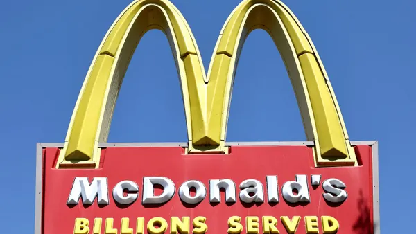A photograph of a red and yellow sign with a giant yellow "M" above a red box that says "McDonald's Billions Served."