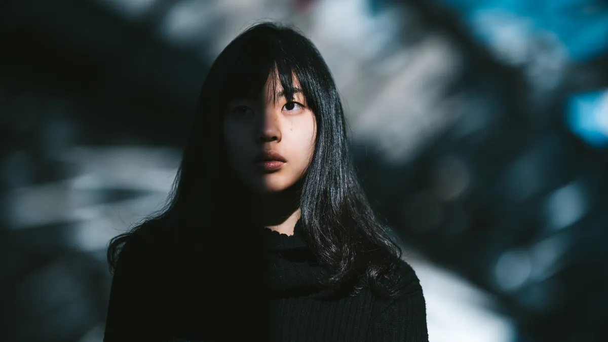 Portrait of a Asian woman, with half of her face lit by the sun and the other half in shadow.