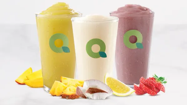 A photo of several beverages in see-through glasses. The glasses have a green Q on them.