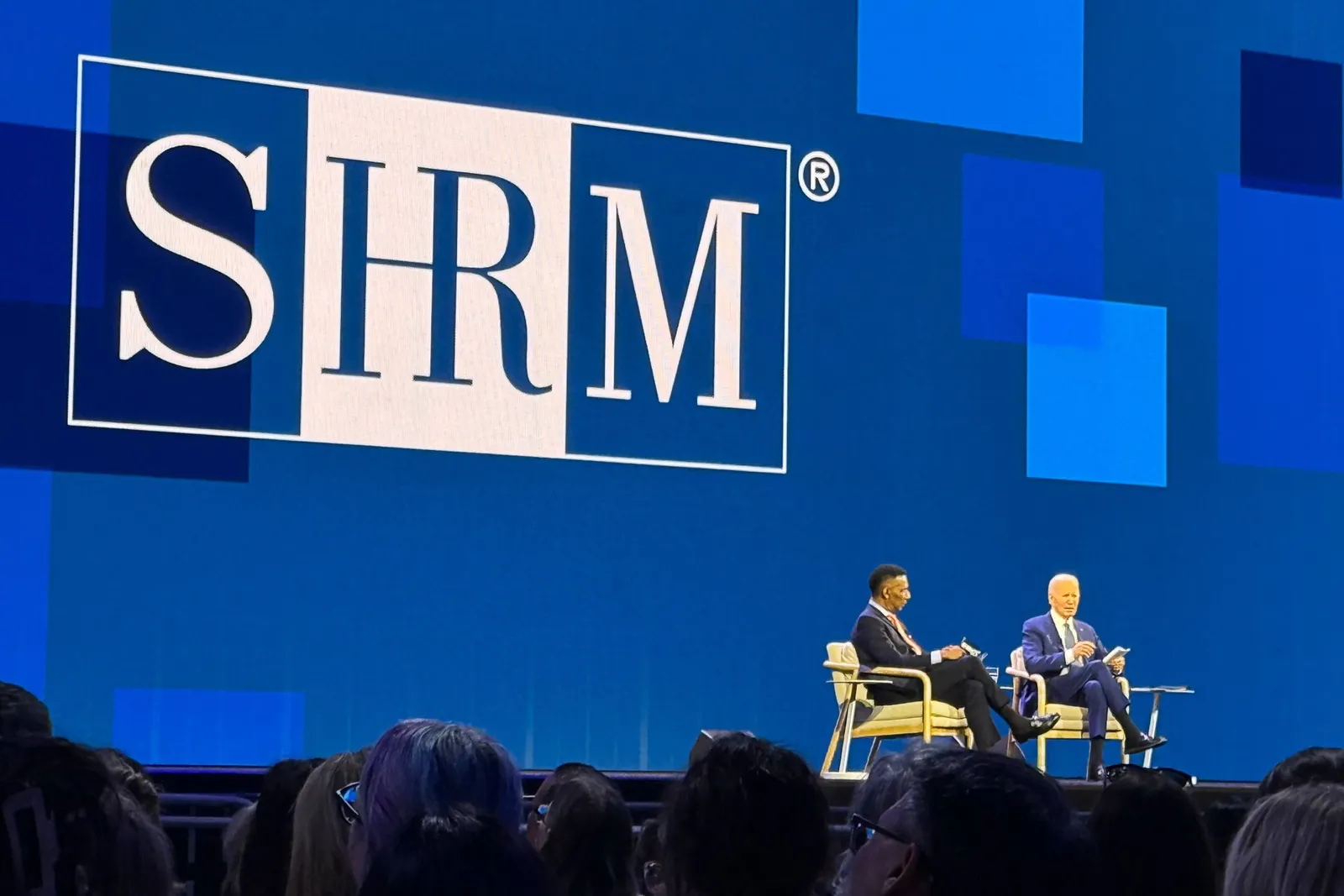 Former president Joe Biden speaks on stage at a conference.