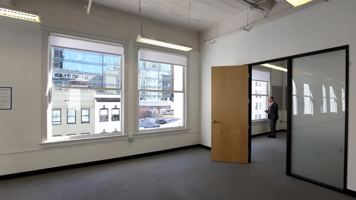 An individual stands alone in a vacant office.