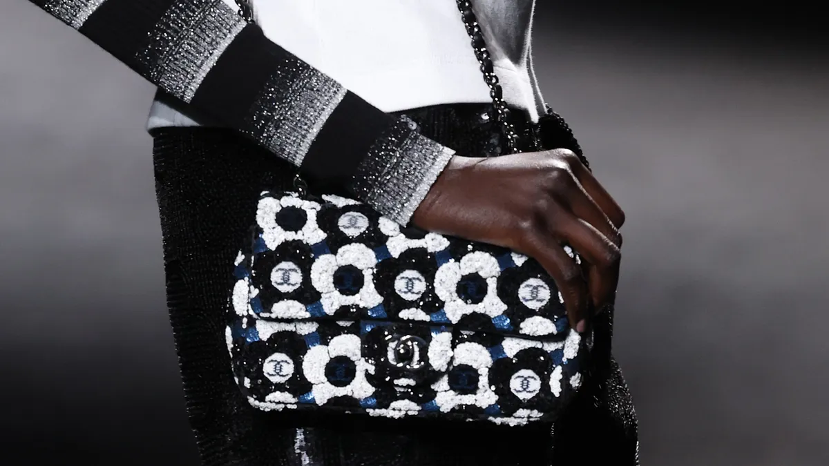 A black-and-white handbag is seen being held on the Chanel runway.