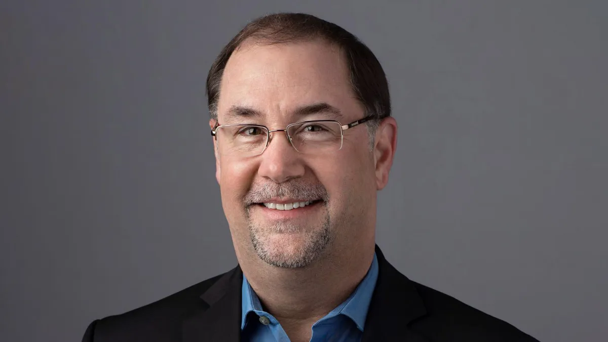 A photograph of a man wearing a suit and smiling