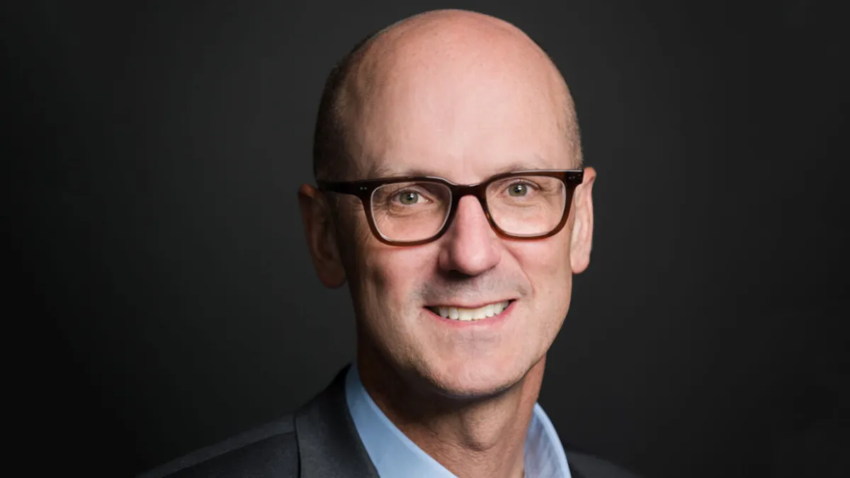 Merit Medical President Joseph Wright wears a light blue shirt, gray jacket and glasses in a headshot.