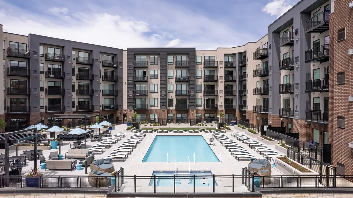 Five-story apartment building surrounding a pool.