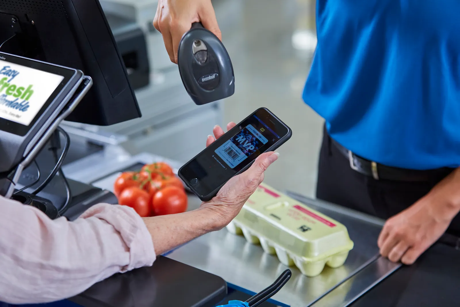 A grocery shopper getting their loyalty program barcode scanned at checkout.