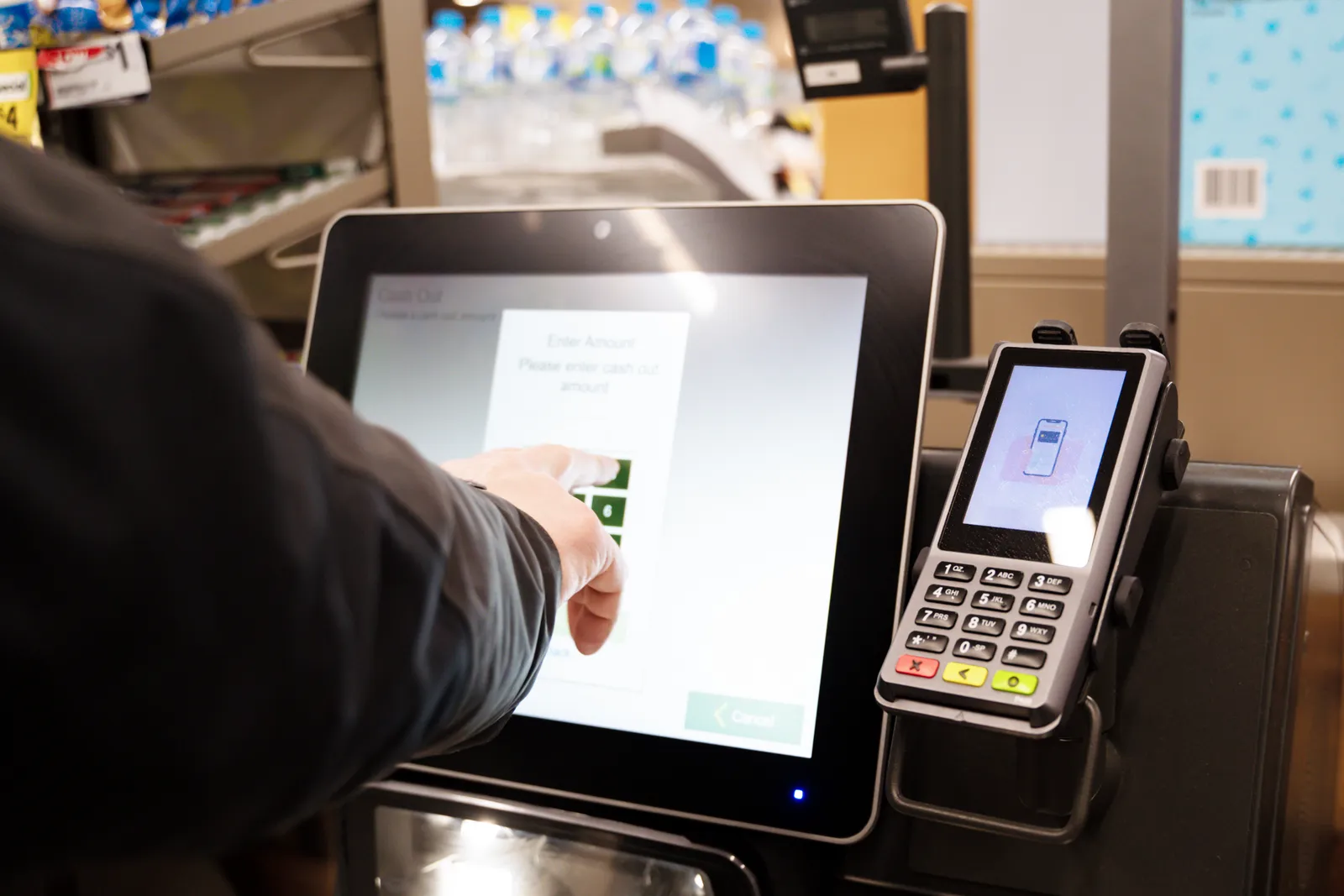 Close-up of a person using a self checkout machine.