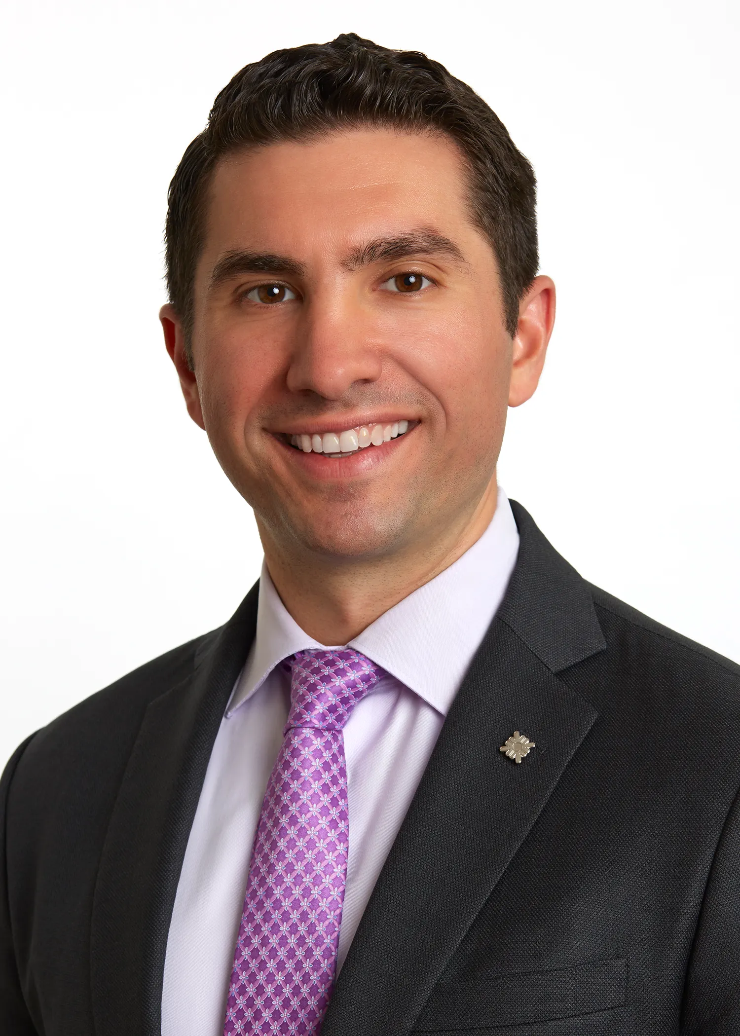 A person wearing a suit and tie smiles for the camera