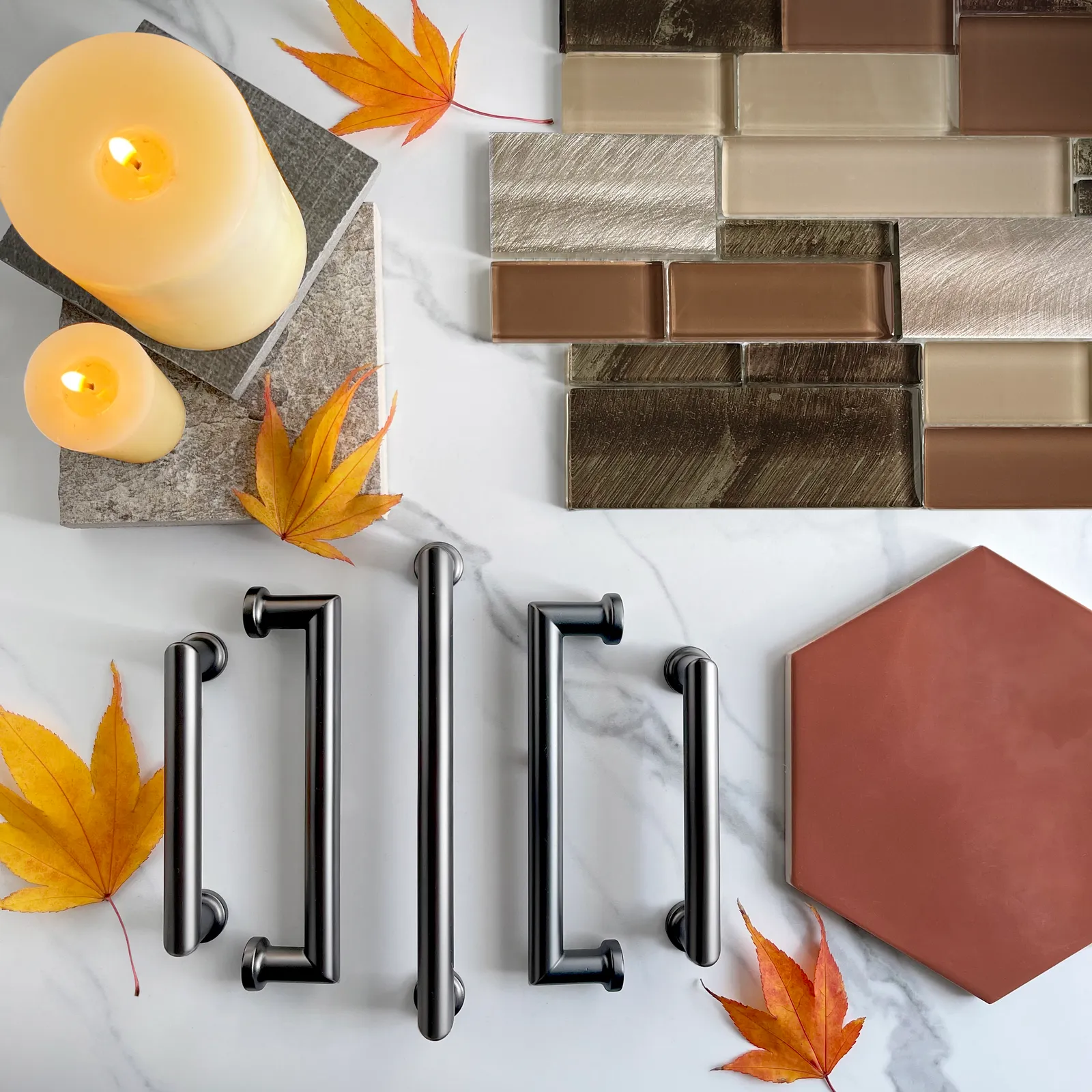 Five pieces of black appliance hardware, set against fall leaves and candles.