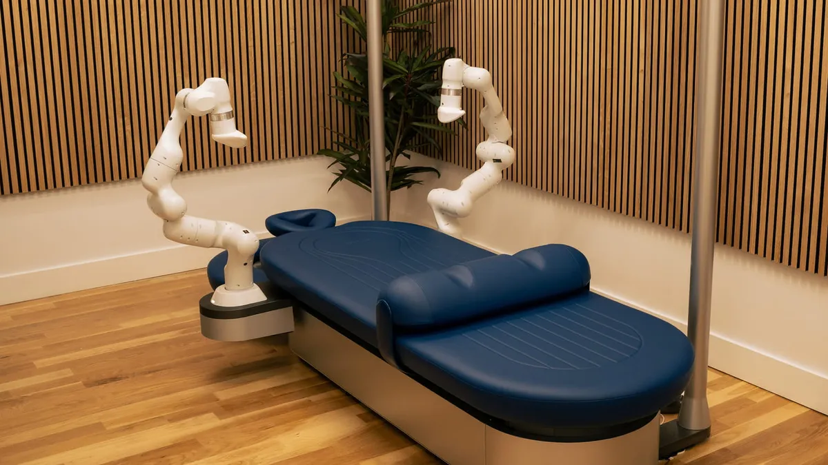 Robotic massage arms beside a blue massage table.