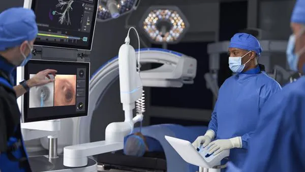 Three people view Intuitive Surgical's Ion robotic system during a procedure setup.