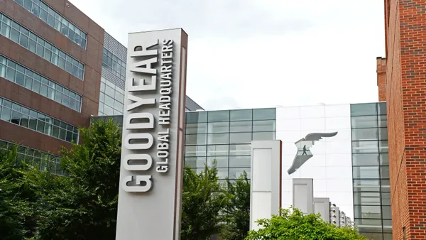 A gray "Goodyear Global Headquarters" sign next to a red brick building.