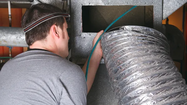 A technician uses air to clean an HVAC system.