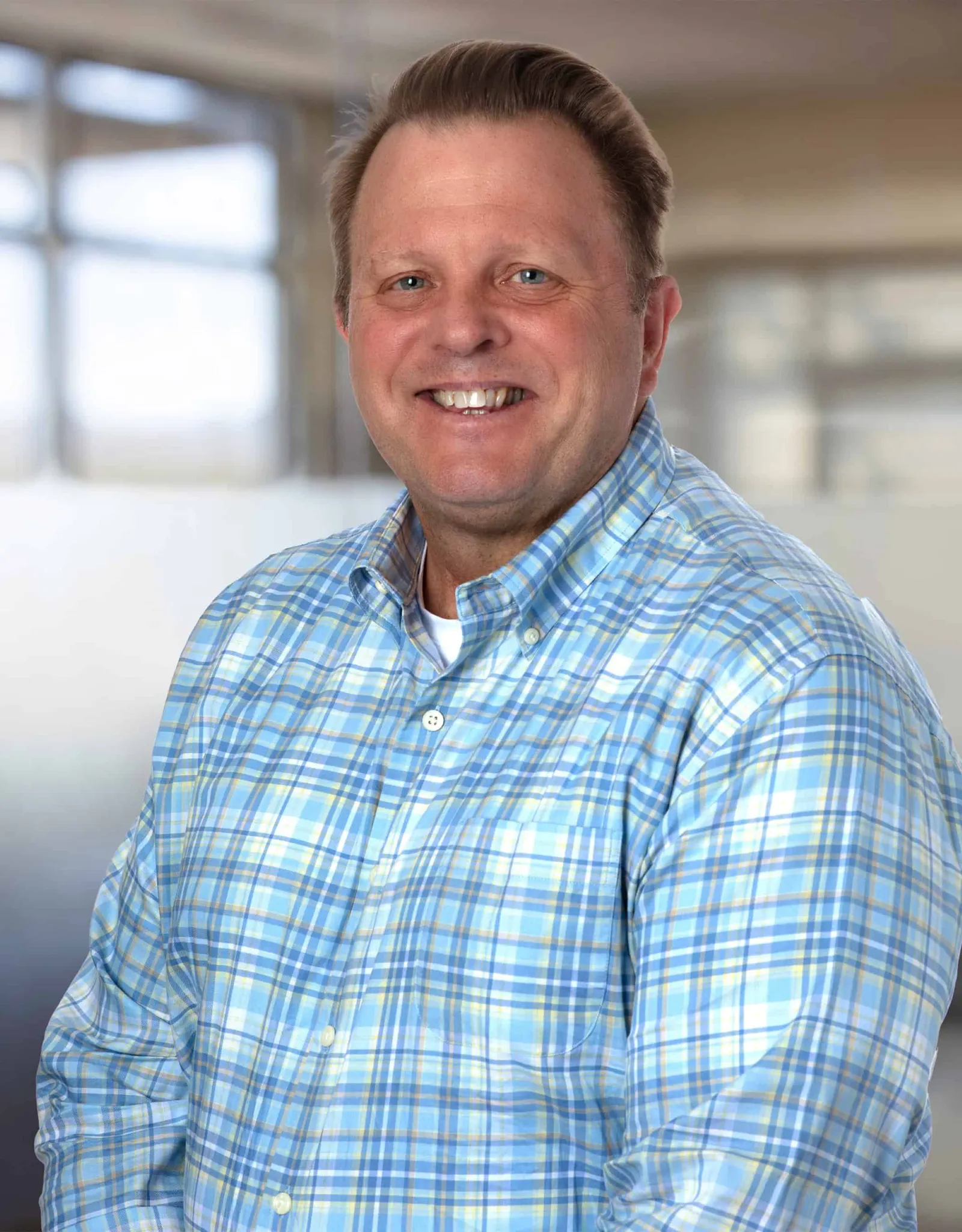 Headshot of a man in a blue plaid shirt